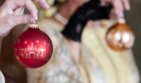 Nahaufnahme von zwei Menschen, die eine Weihnachtskugel in der Hand halten
