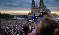 Eine Person hält ihr Smartphone in die Luft und fotografiert eine Menschenmenge