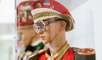 Eine Figur steht in Seitenansicht in einem Karnevalskostüm hinter einer Glasscheibe