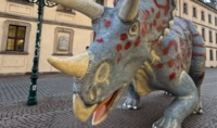 Eine Dinosaurier-Statue steht vor einer Häuserfront