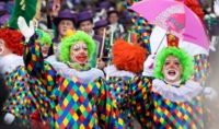 Zwei Menschen in Clownskostümen stehen vor verkleideten Menschen
