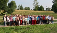 Eine Gruppe von Menschen steht auf einem Weg mit Bäumen und Wiesen im Hintergrund