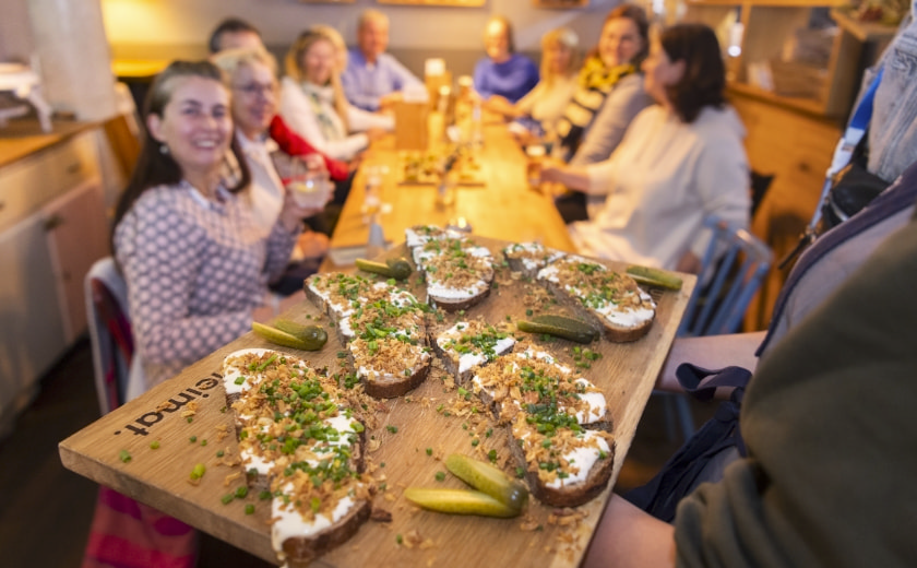 Eine Gruppe von Menschen sitzt an einem Tisch und es wir Essen auf einem Tablett gebracht – Tourismus Fulda