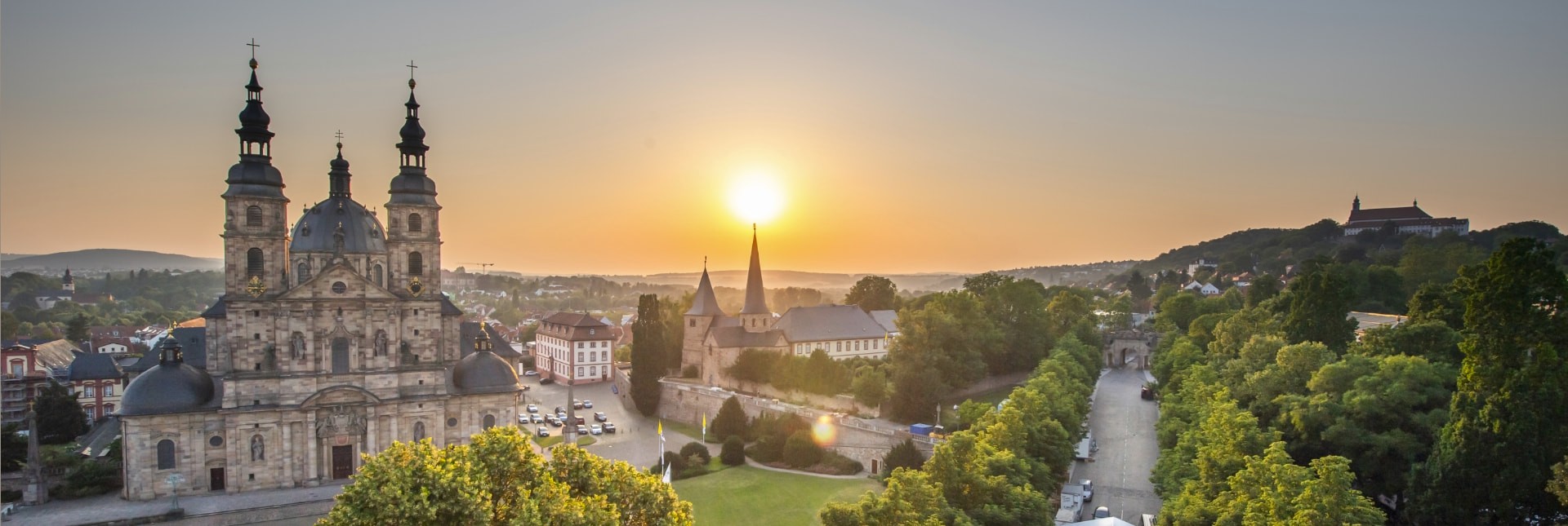 Ein Restaurant mit gedeckten Tischen und Stühlen für das Abendessen, im Hintergrund ist die Fuldaer Innenstadt – Tourismus Fulda